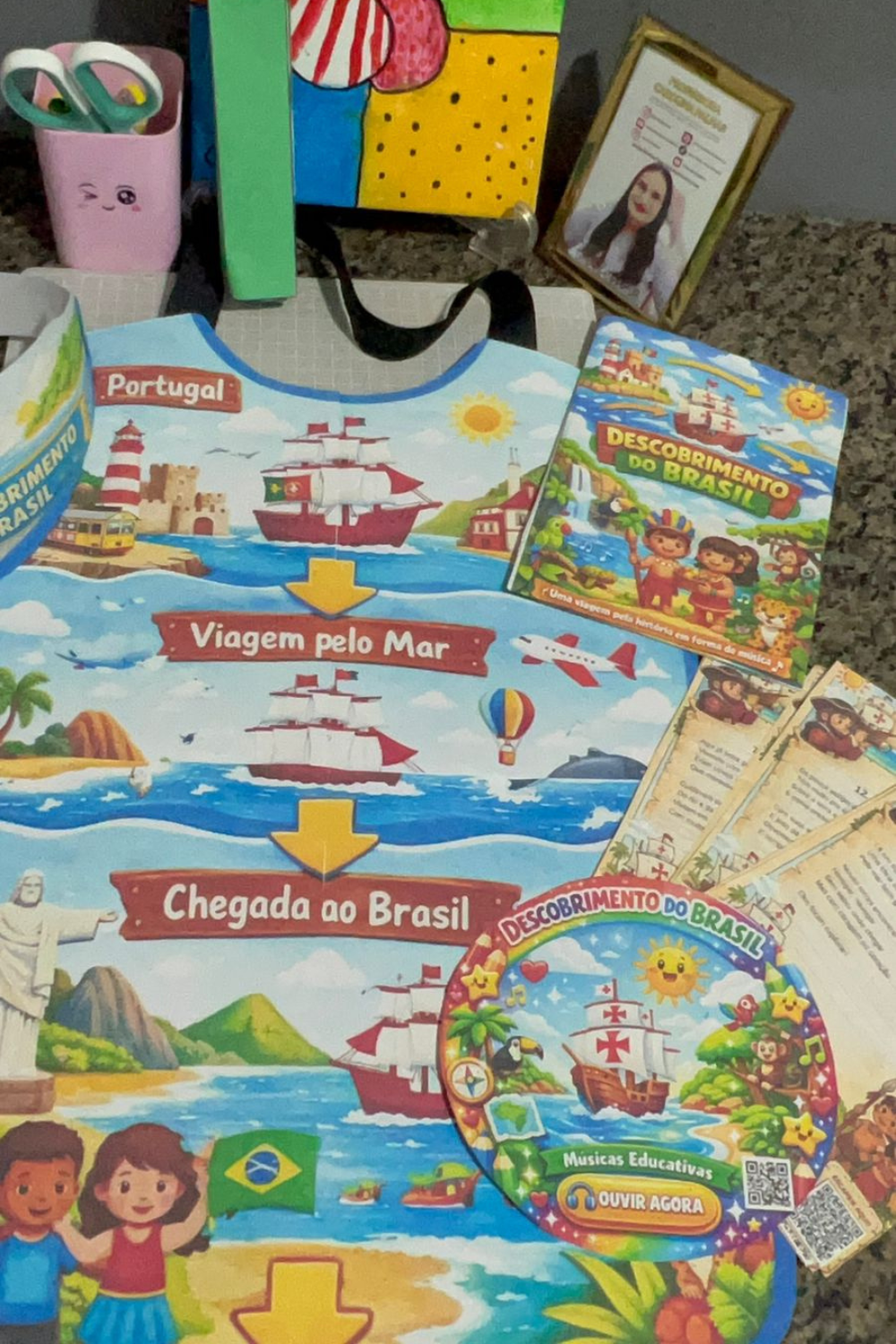 KIT COM CD PEDAGÓGICO, AVENTAL, MICROFONE E COROA DO DIA DO DESCOBRIMENTO DO BRASIL